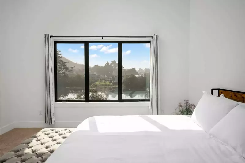 This bedroom has an serene view of the lake from the comfy bed.