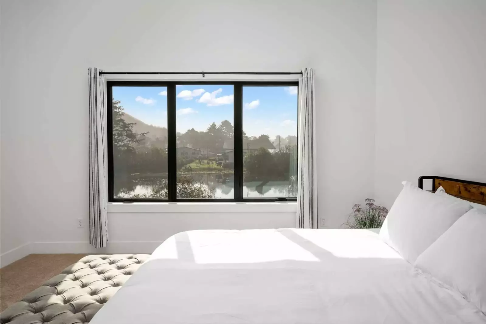 This bedroom has an serene view of the lake from the comfy bed.