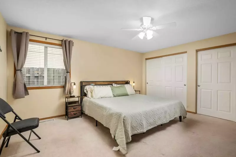 This bedroom has a lot space, large closets, a ceiling fan, and a king bed.