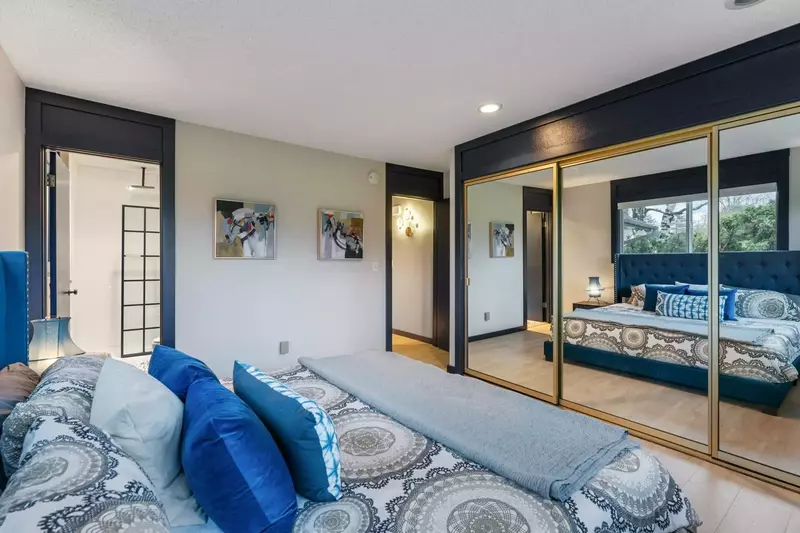 This bedroom has a comfy bed, expansive closet space, and full length mirrors.