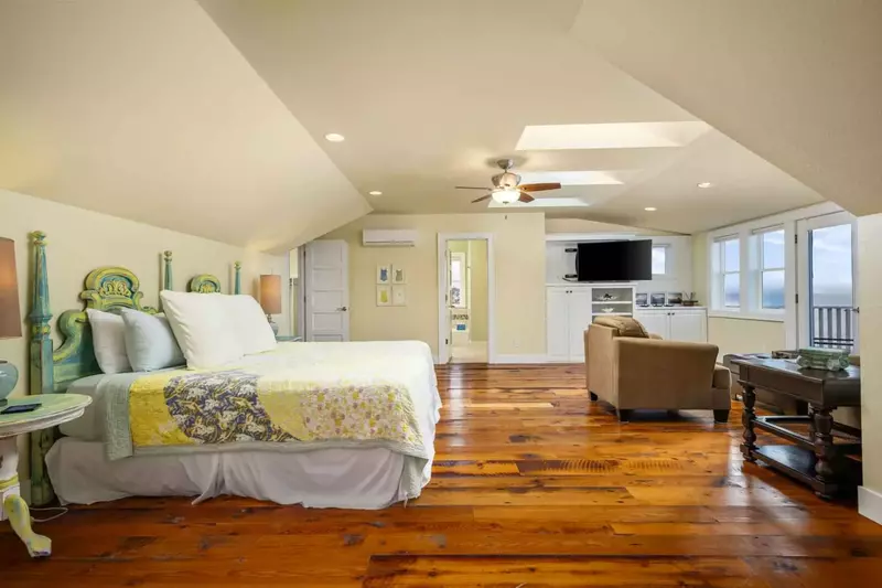 The primary bedroom has a king bed, lots of space, an en suite bathroom, deck access, a smart tv, beautiful hardwood floors, and more.