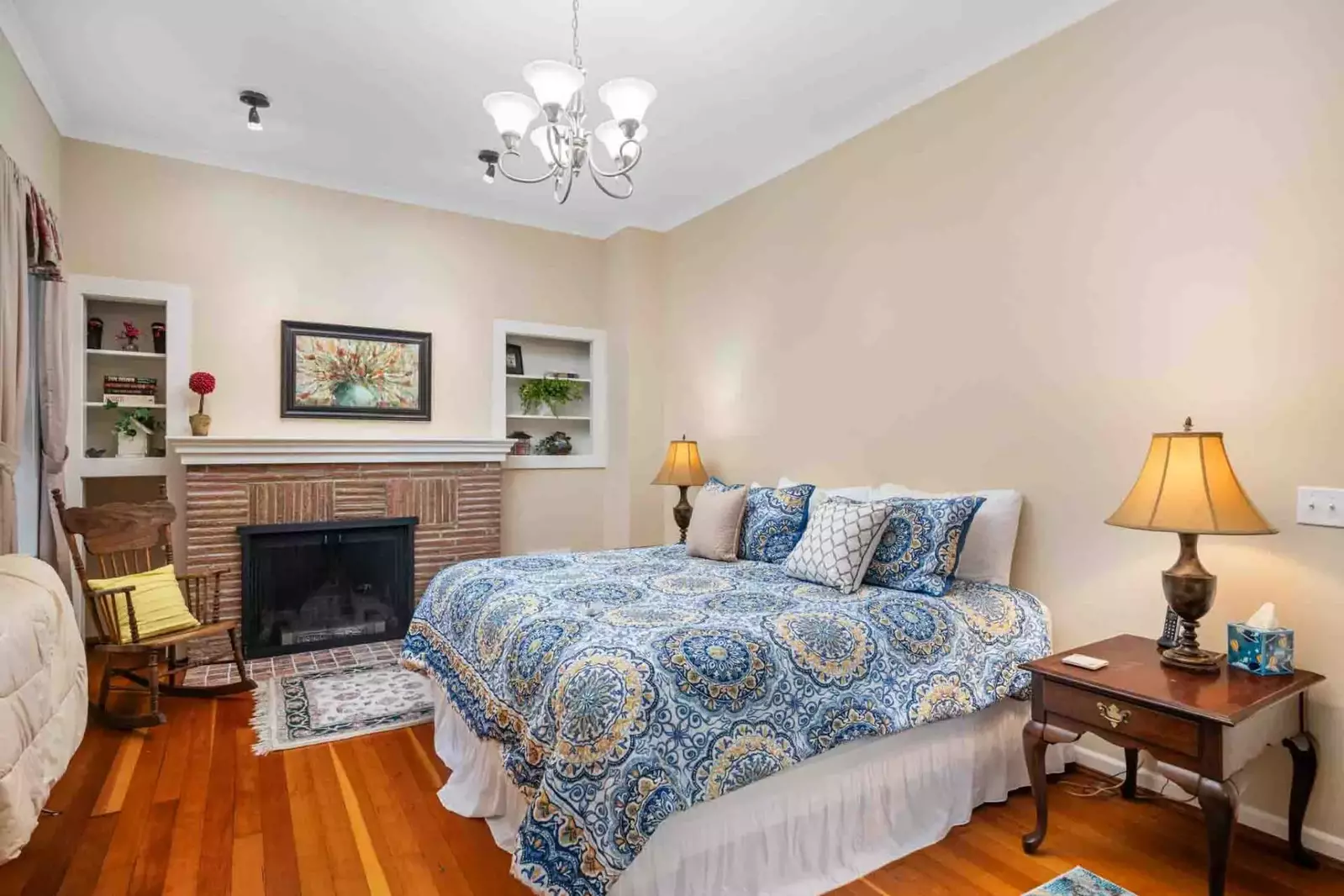 This vintage bedroom has an incredibly comfy bed and a fireplace.
