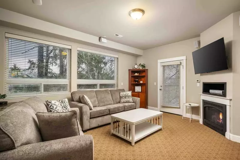 Gather in the cozy living room, where a love seat and microfiber couch surround a gas fireplace and a large wall-mounted TV for the family to relax.