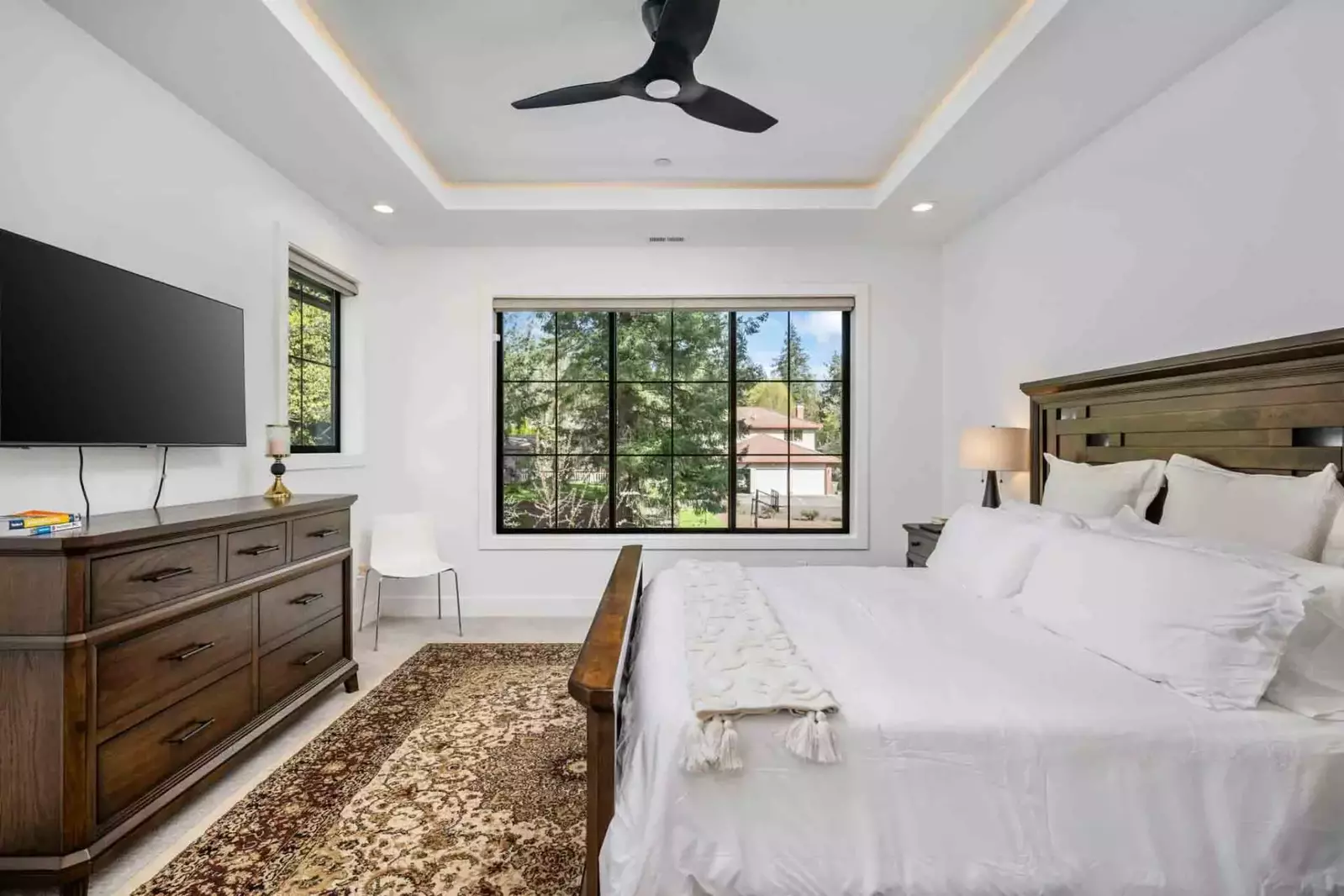 This bedroom has a tv, a fan, and a king bed.