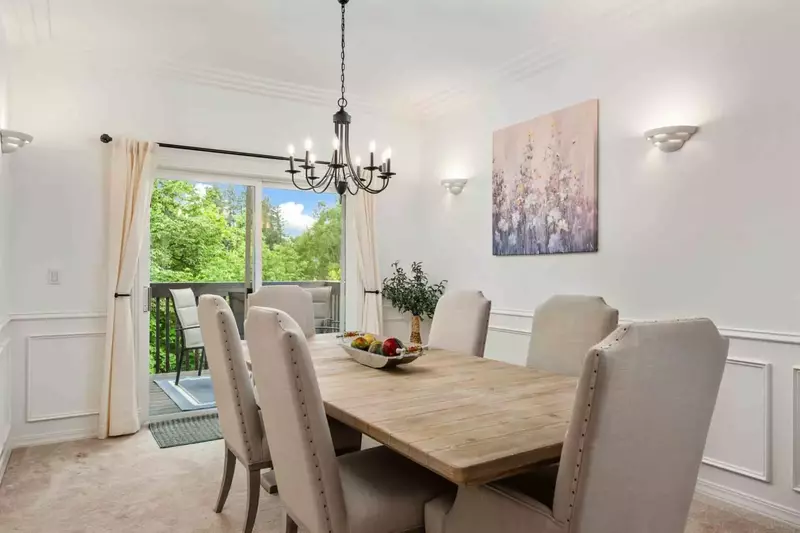 The dining room is near a window with a pleasant view of lush trees.