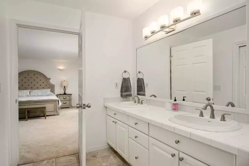 This bedroom features an en suite bathroom with two sinks.