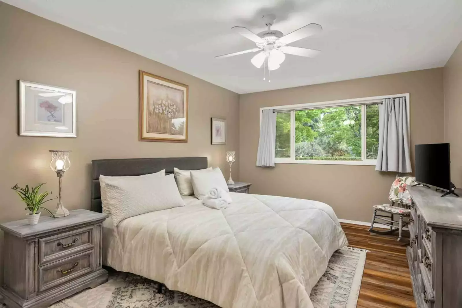 This bedroom has a tv, a fan, and an incredibly comfortable bed.
