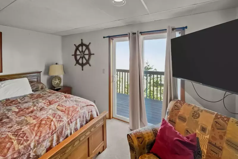 This bedroom has a comfy bed, smart tv, and view of the sea.