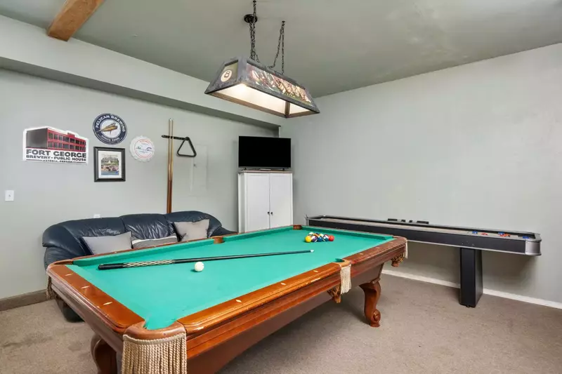 Converted game room with pool table, shuffleboard, TV and seating.