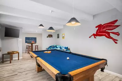 Two game rooms with both ping-pong and pool tables, sofa, TV, refrigerator and elevated table.