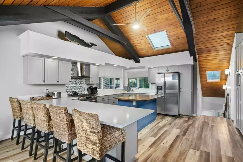 Gather at the breakfast bar overlooking the Chef's kitchen with large gas range, stainless-steal appliances and plenty of skylight counters.