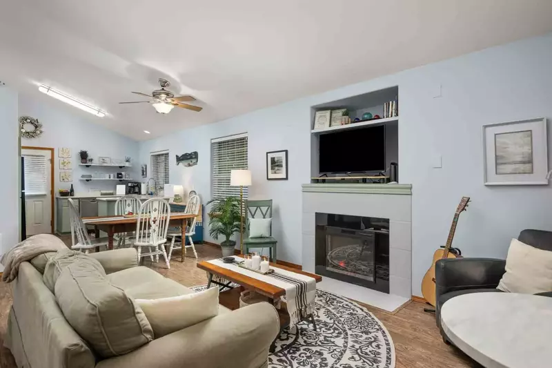 The living room is a charming space with a fireplace, tv, acoustic guitar, games, and comfortable seating.