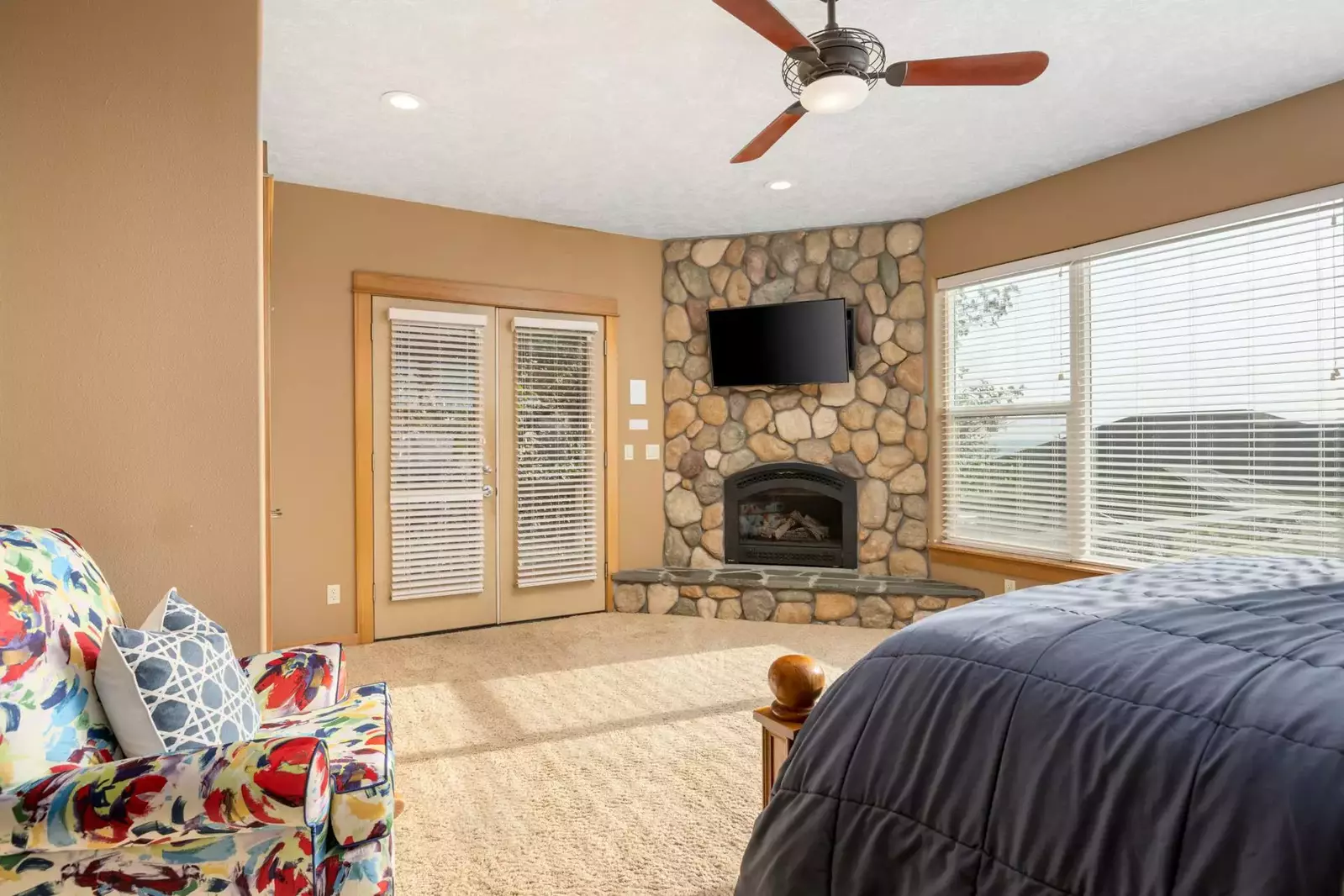 This bedroom has a tv, fireplace, ceiling fan, great natural light, a very comfy bed, and more!