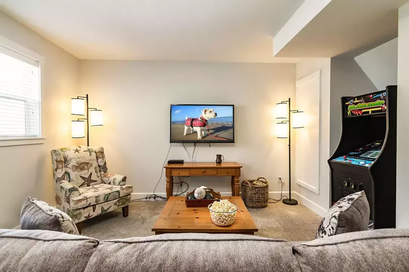 Descending downstairs you will find a wonderfully appointed bonus room with a shuffleboard table, arcade game, and flat-screen TV.