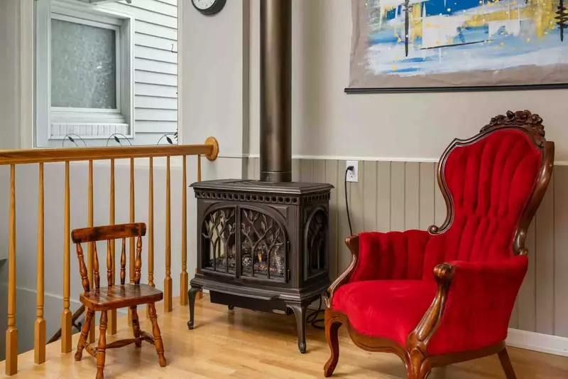 Enjoy sitting in this comfy chair next to a warm decorative stove.