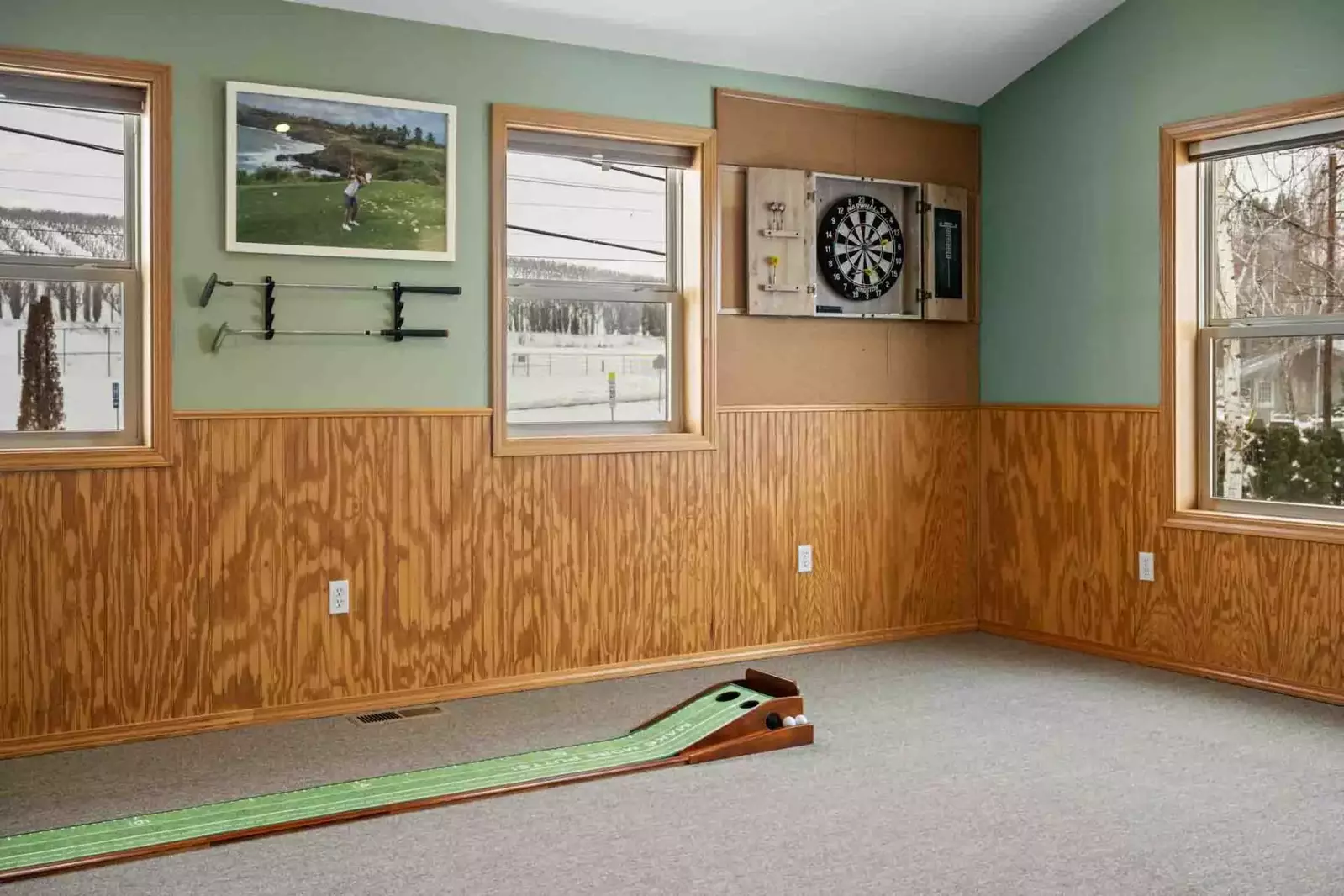 A mini putting green and a dart board are additional fun parts of the game room.