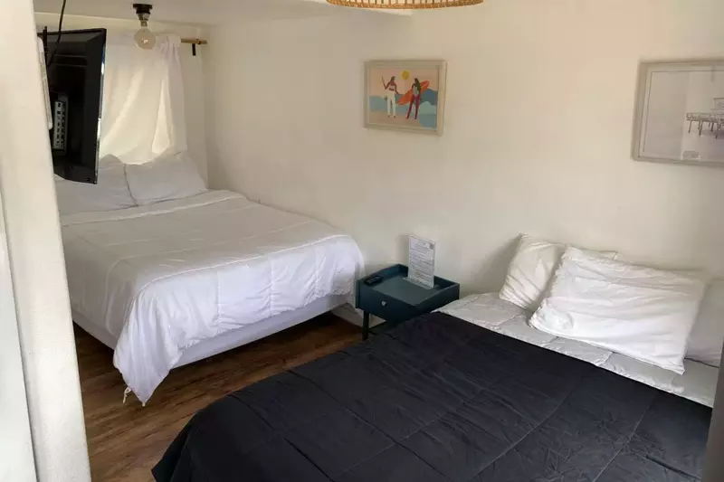 A queen bed and full bed in a shared space.