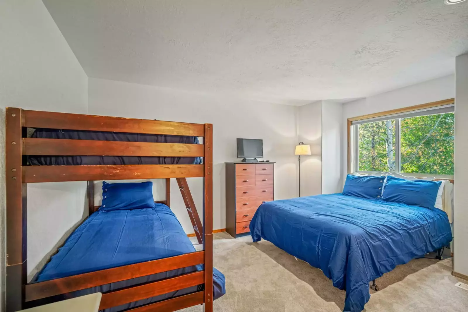 Twin bunk beds along with a queen bed, includes storage space an TV