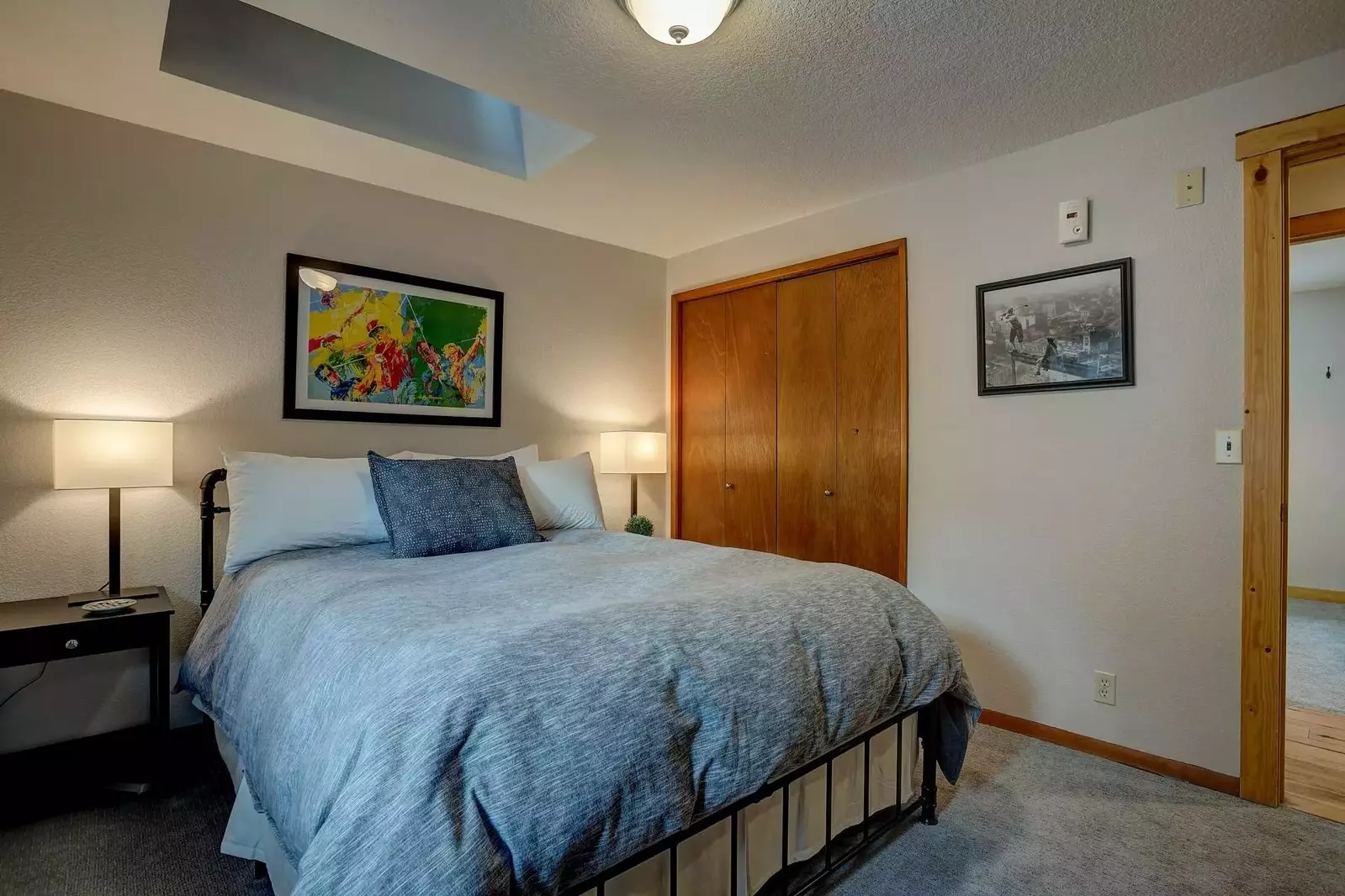 Master bedroom with ensuite full bathroom, dresser, end tables, and reading lamps.