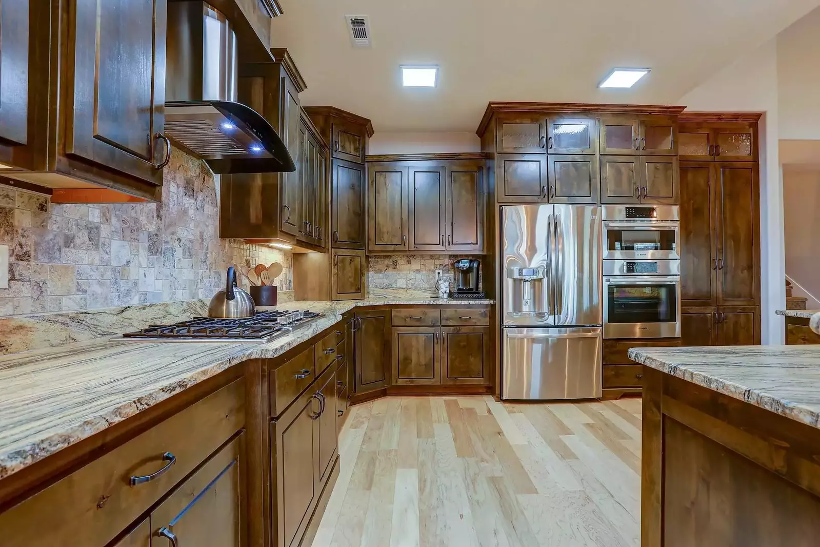 Stainless steel Bosch appliances, granite countertops, custom cabinets, and hardwood floors beckon in the kitchen