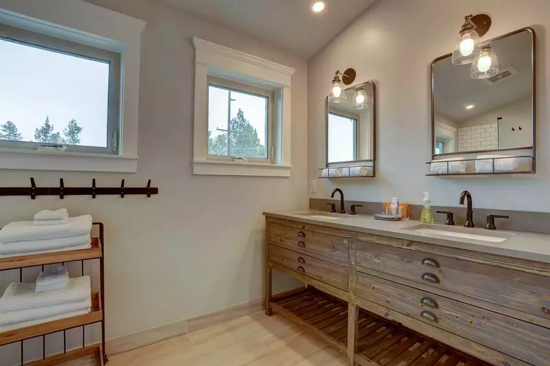 New bathroom off bunk room features dual sinks and mirrors