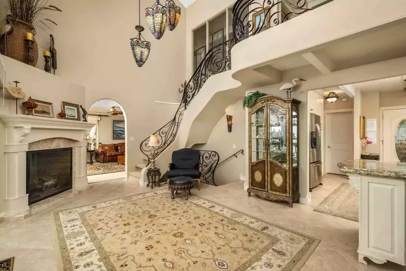 A beautiful area with high ceilings, a fireplace, and a beautiful stairway.