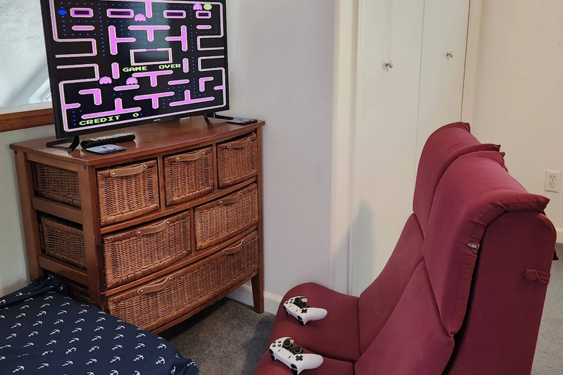 Cozy upstairs game nook with retro arcade fun and comfortable seating for relaxing after a beach day.