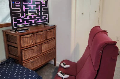 Cozy upstairs game nook with retro arcade fun and comfortable seating for relaxing after a beach day.